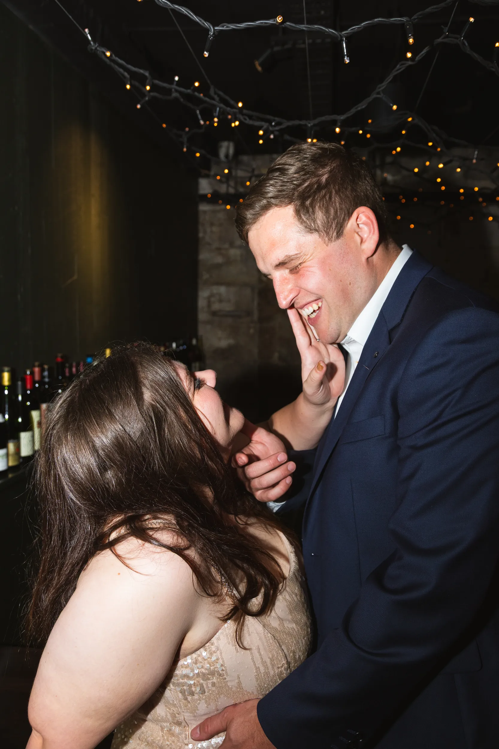 Carlie and Iain joyful laughter moment in rustic cellar venue with string lights capturing their happiness