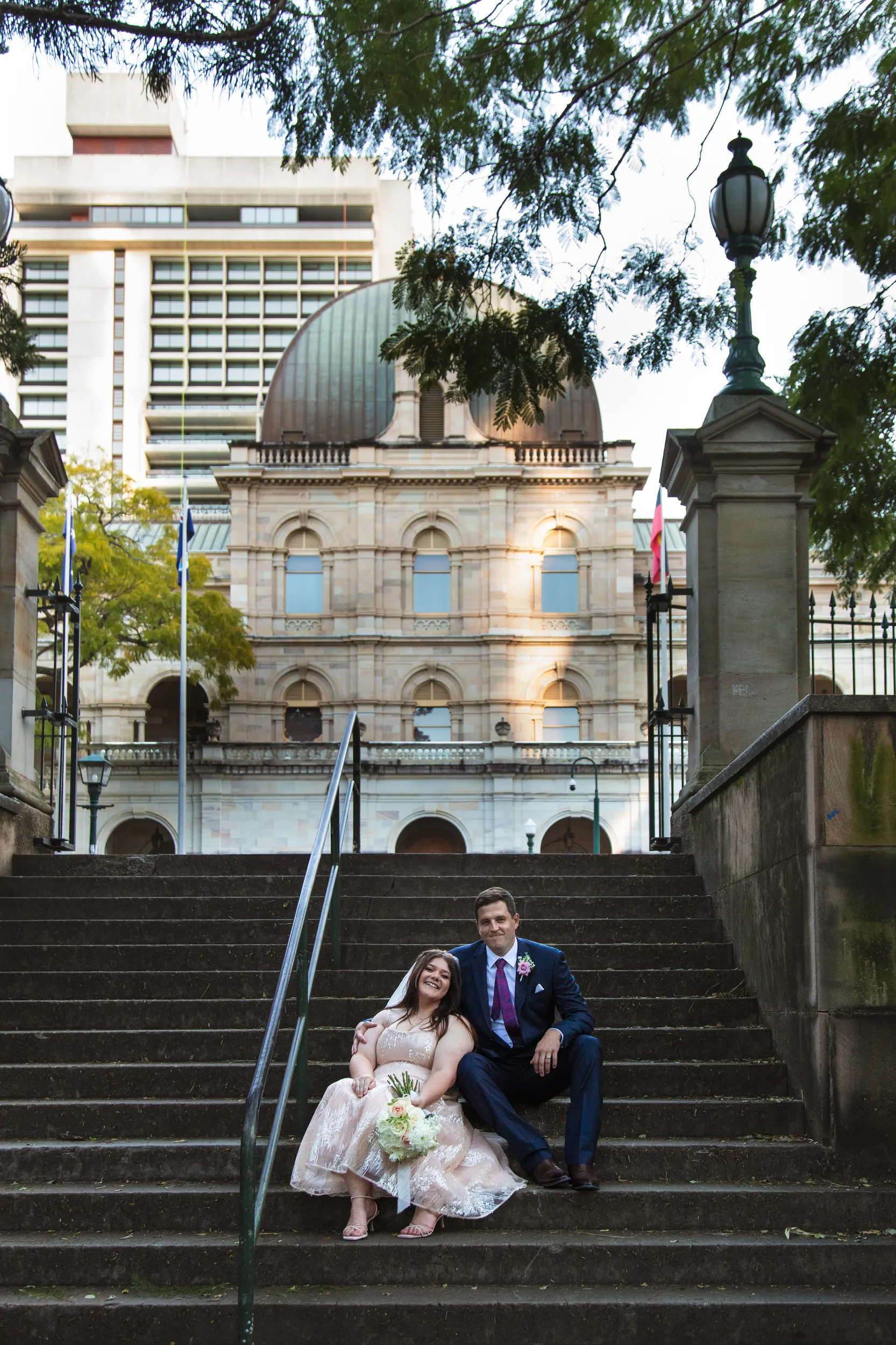 Carlie and Iain beautiful portrait sitting on stone steps in front of historic domed building during golden hour