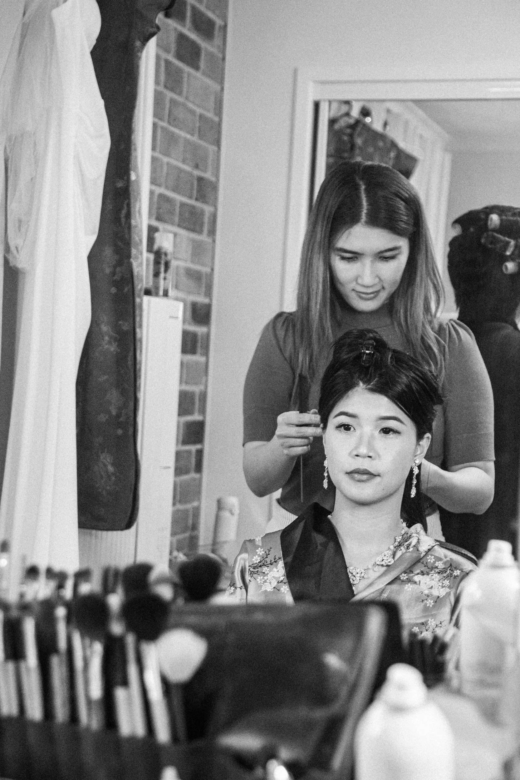Huiyu getting ready black and white photo with hair styling and wedding dress hanging in background