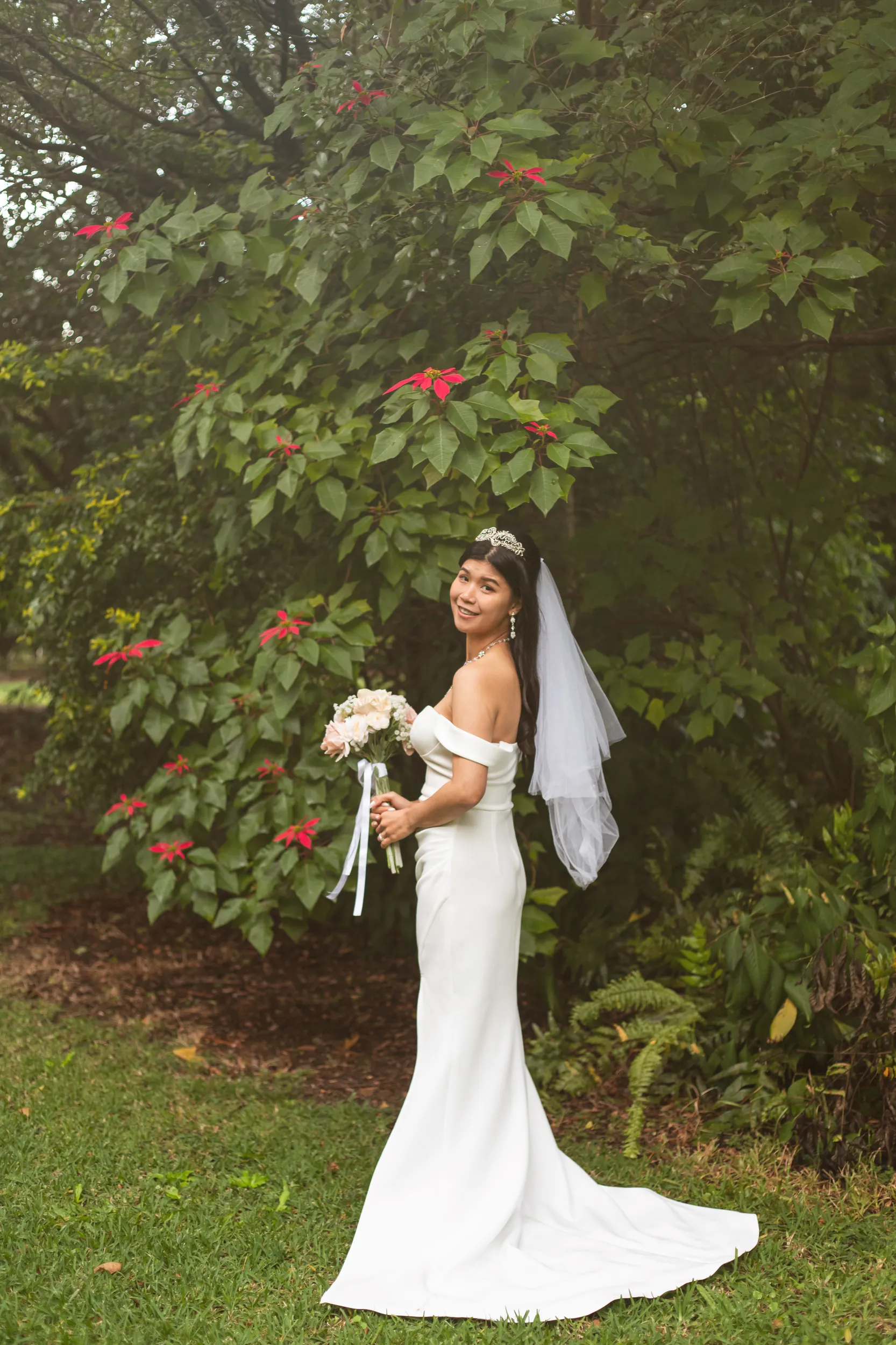 Huiyu stunning solo bridal portrait in white off-shoulder dress with crystal tiara and veil in lush garden