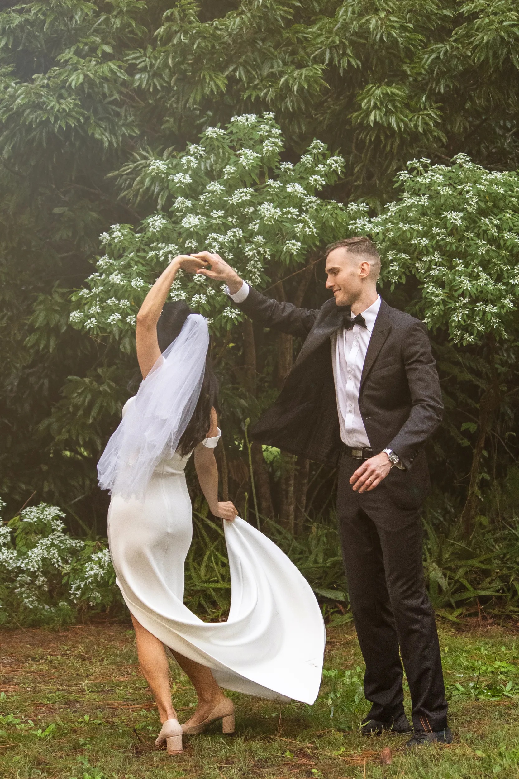 Huiyu and Chris joyful dancing moment with groom spinning bride in flowing white dress in garden