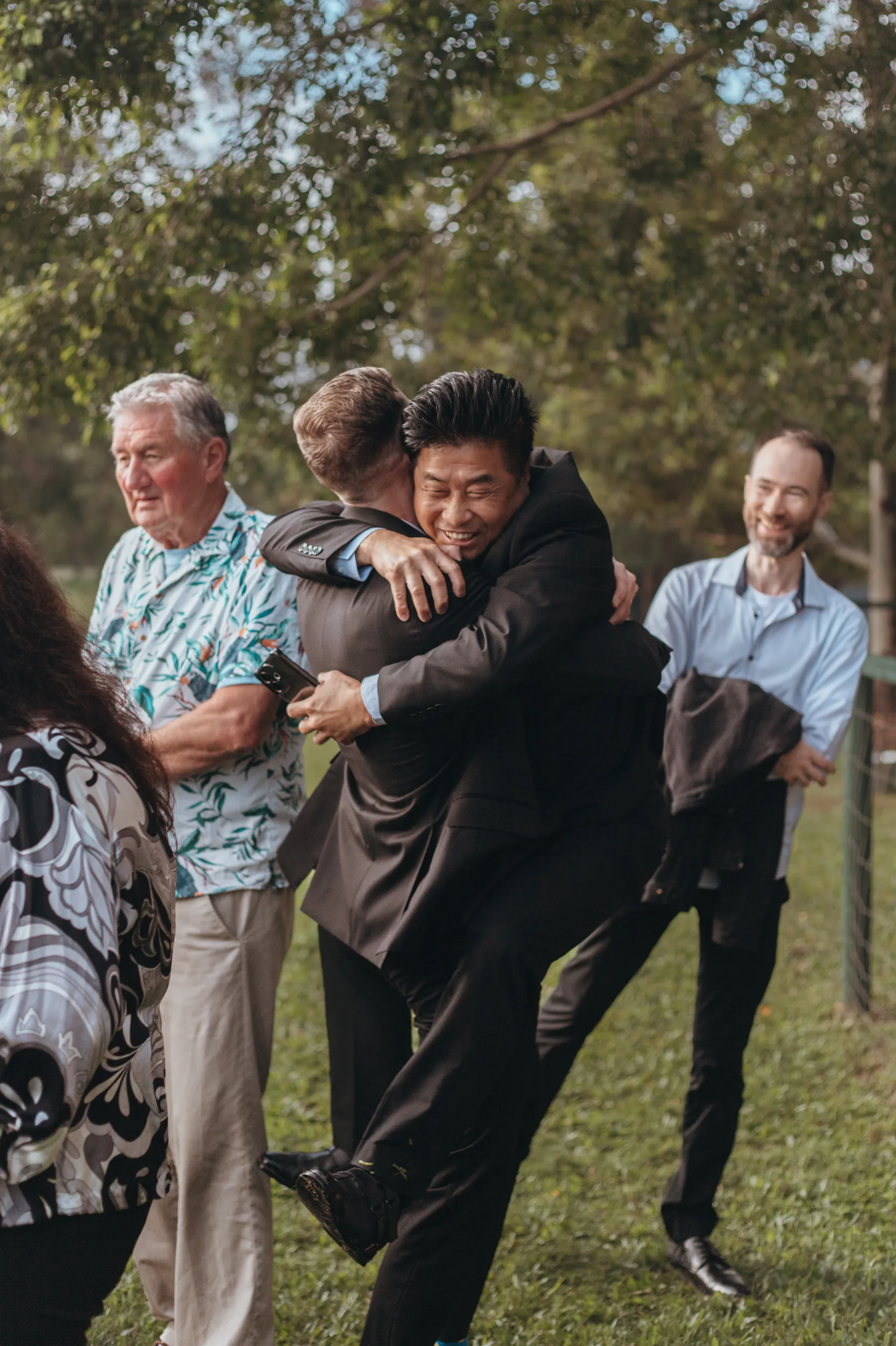 Chris emotional moment hugging family members after wedding ceremony with guests celebrating in garden setting