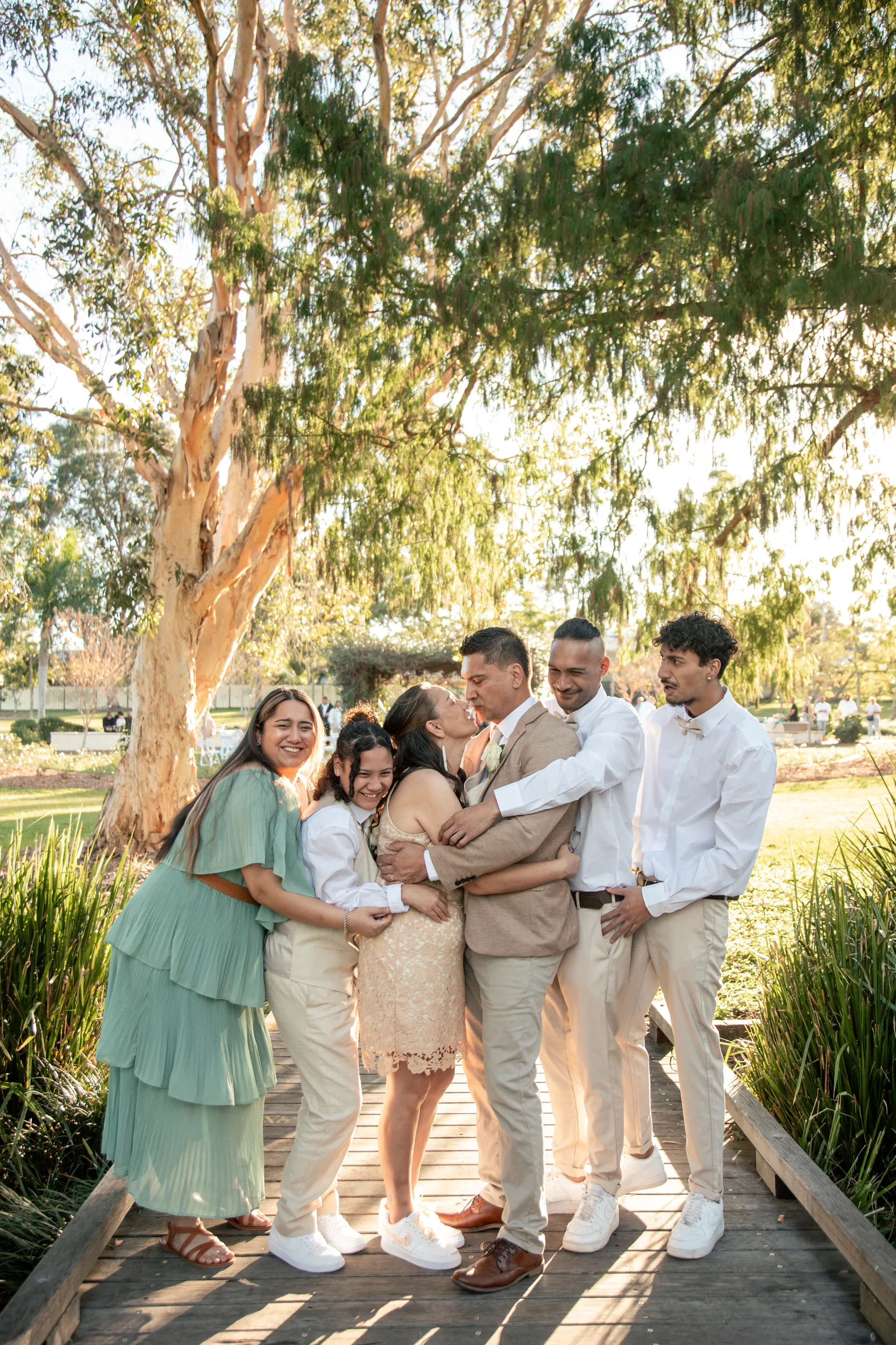 Emotional family embrace on boardwalk during golden hour with couple and loved ones celebrating